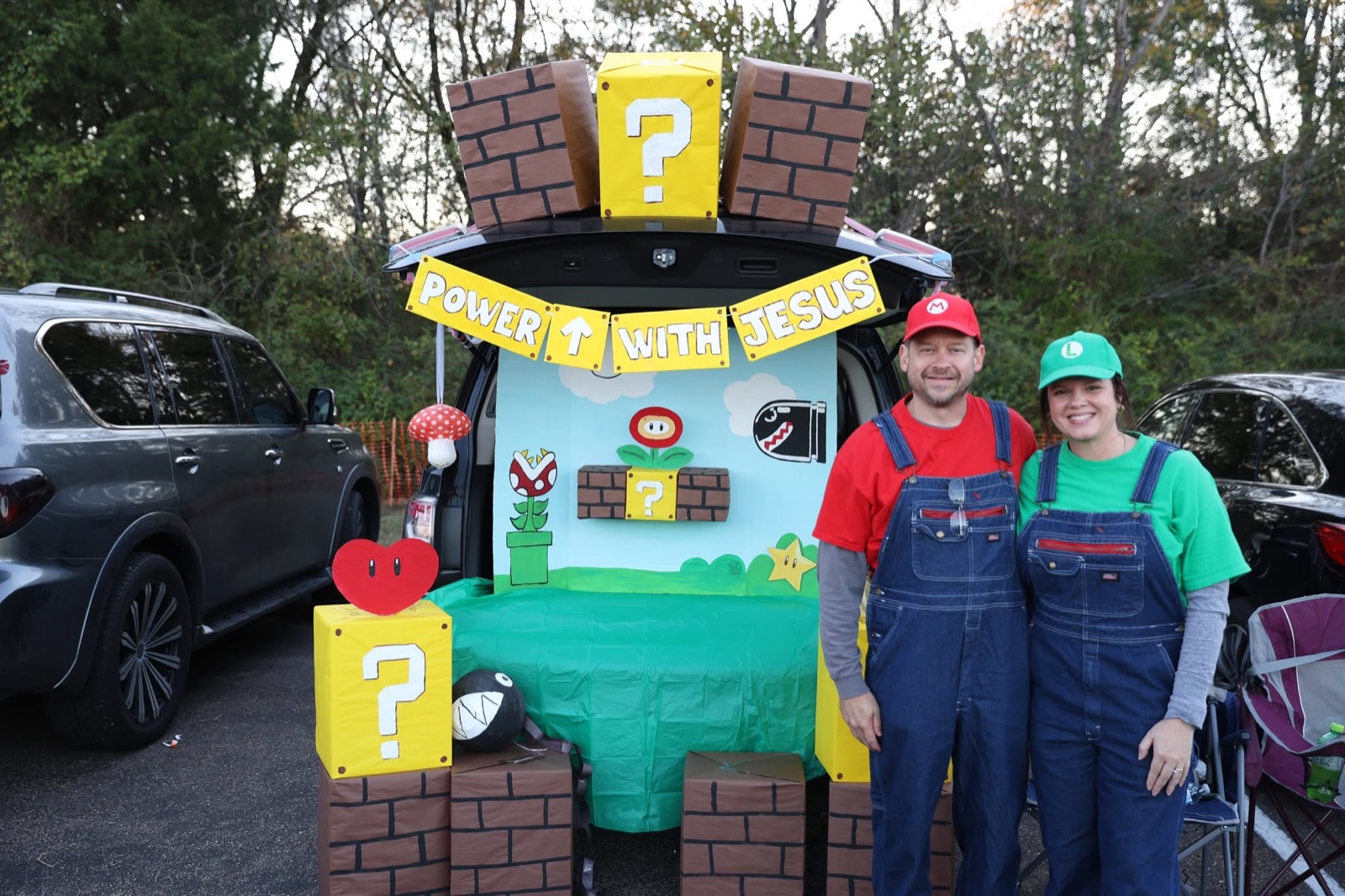 A trunk built like a Super Mario level with question blocks and a green pipe, a couple dressed as Mario and Luigi beside it.